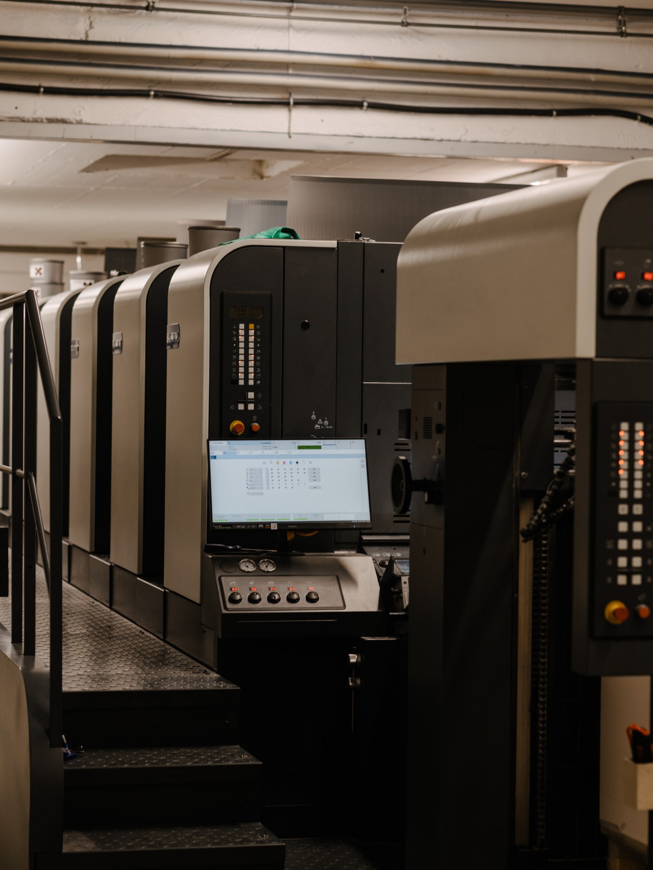 Steidl's Manroland offset printing press with beige and black exterior and digital control panel in warehouse setting.