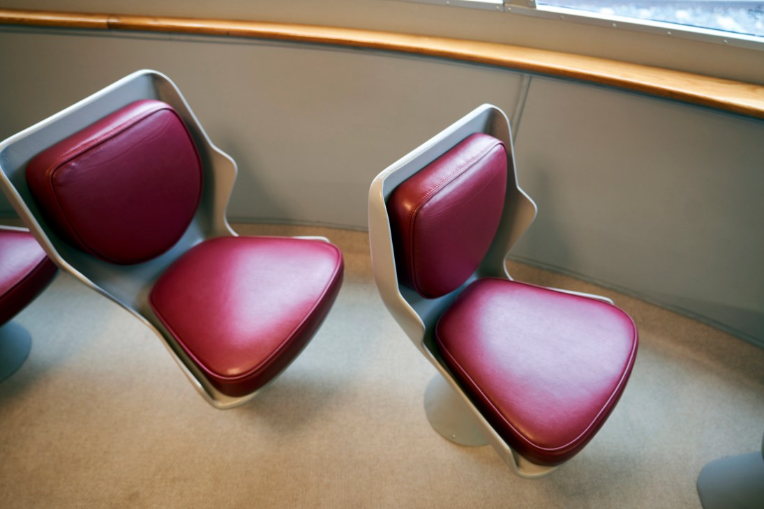 Close-up of red leather train seats with white curved frames inside L'Arlecchino vintage railway carriage