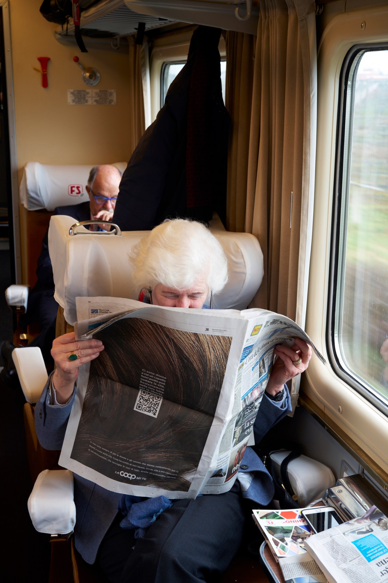 Passengers reading newspapers aboard the L'Arlecchino train