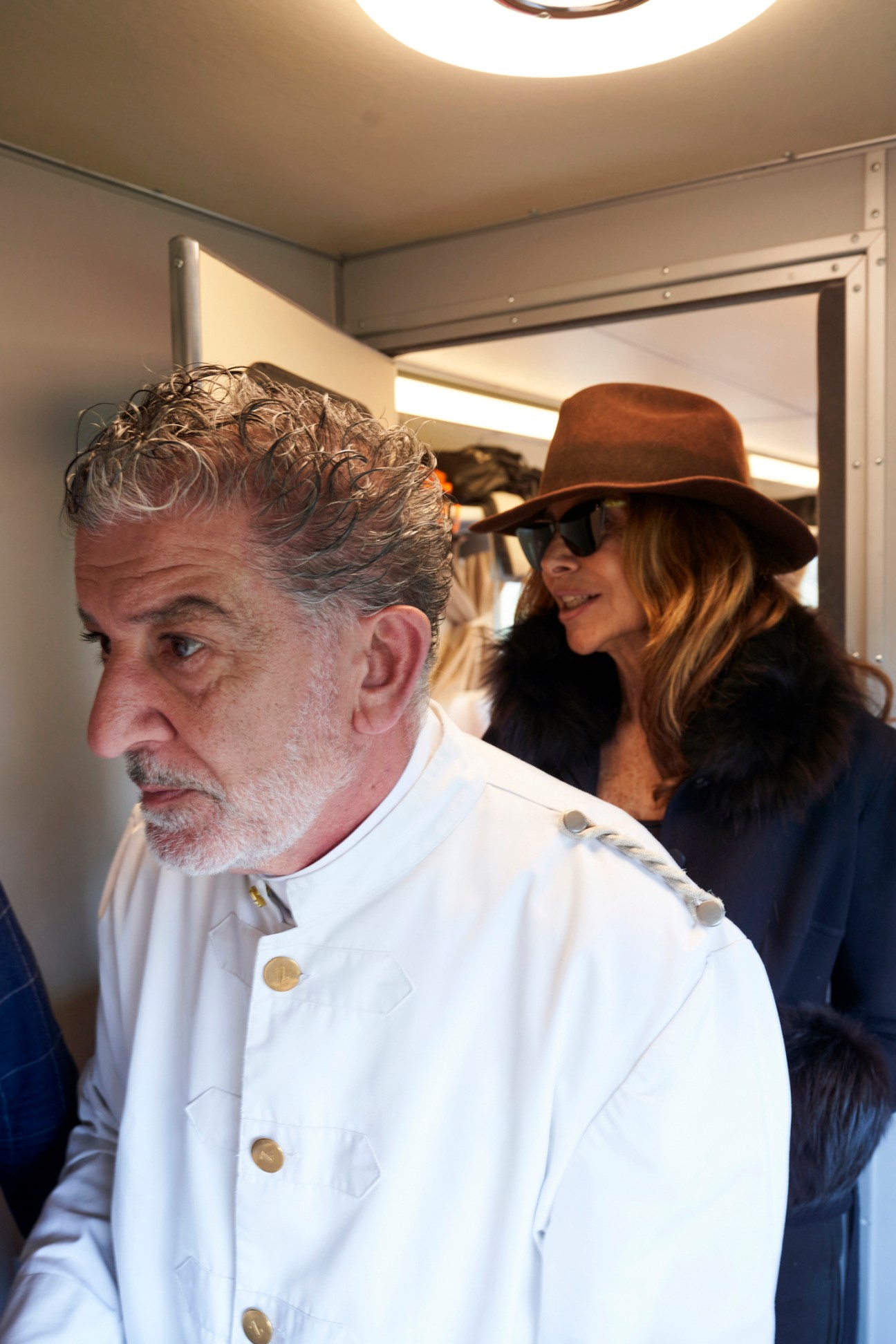 Train staff member in white uniform moving through busy carriage