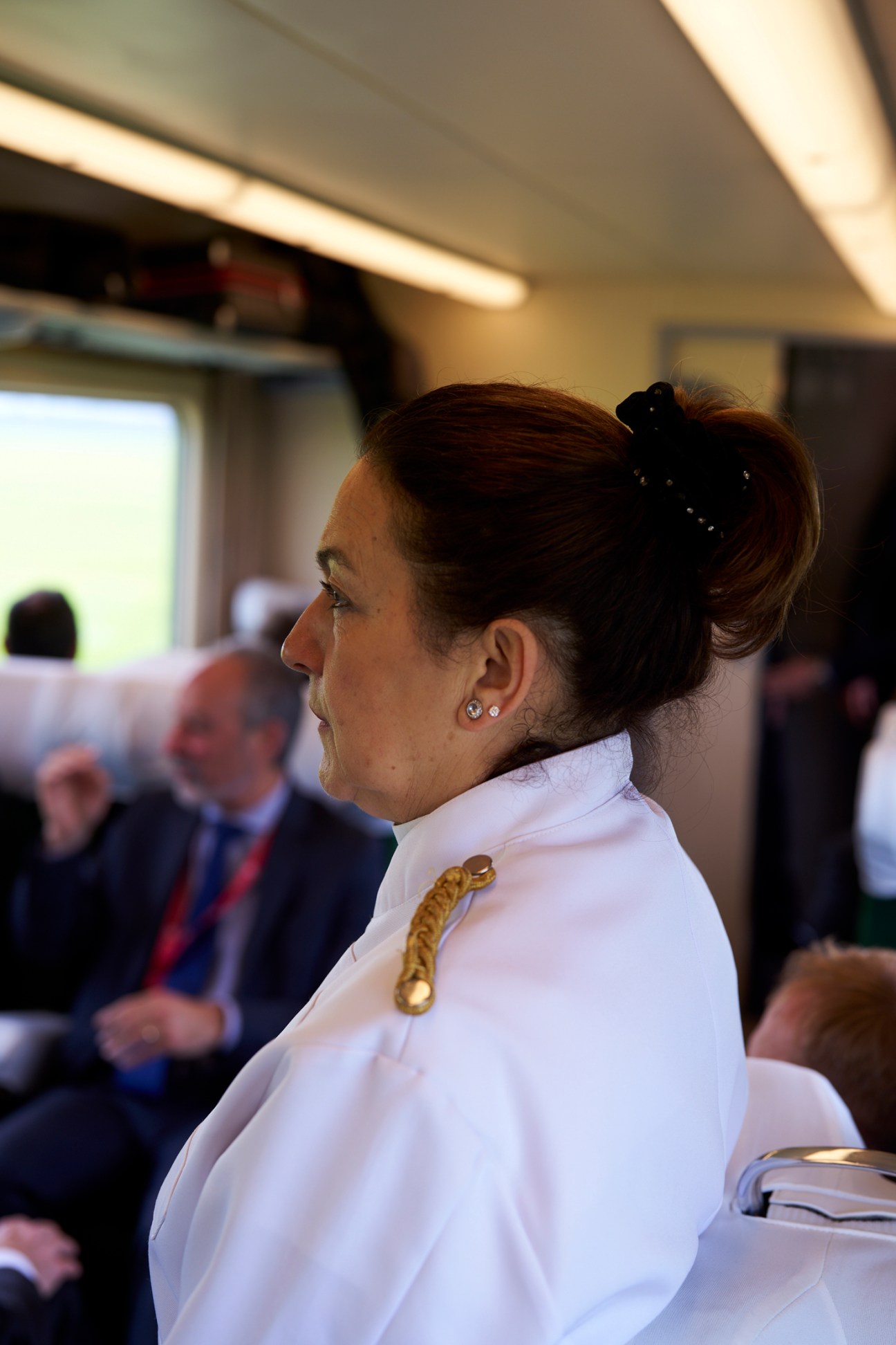 Waiter in white uniform serving passengers in crowded train carriage