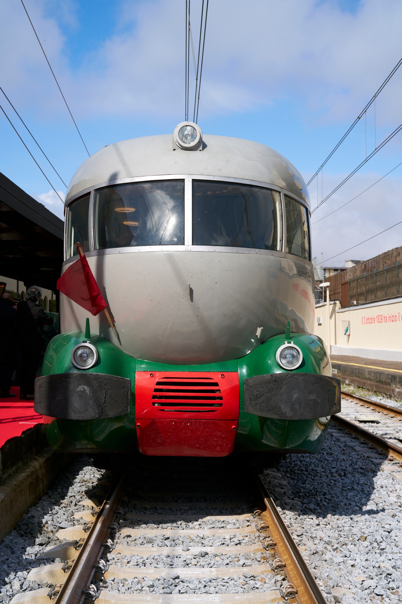 Front view of vintage ETR 252 L'Arlecchino train with streamlined silver body and green-red livery at station platform