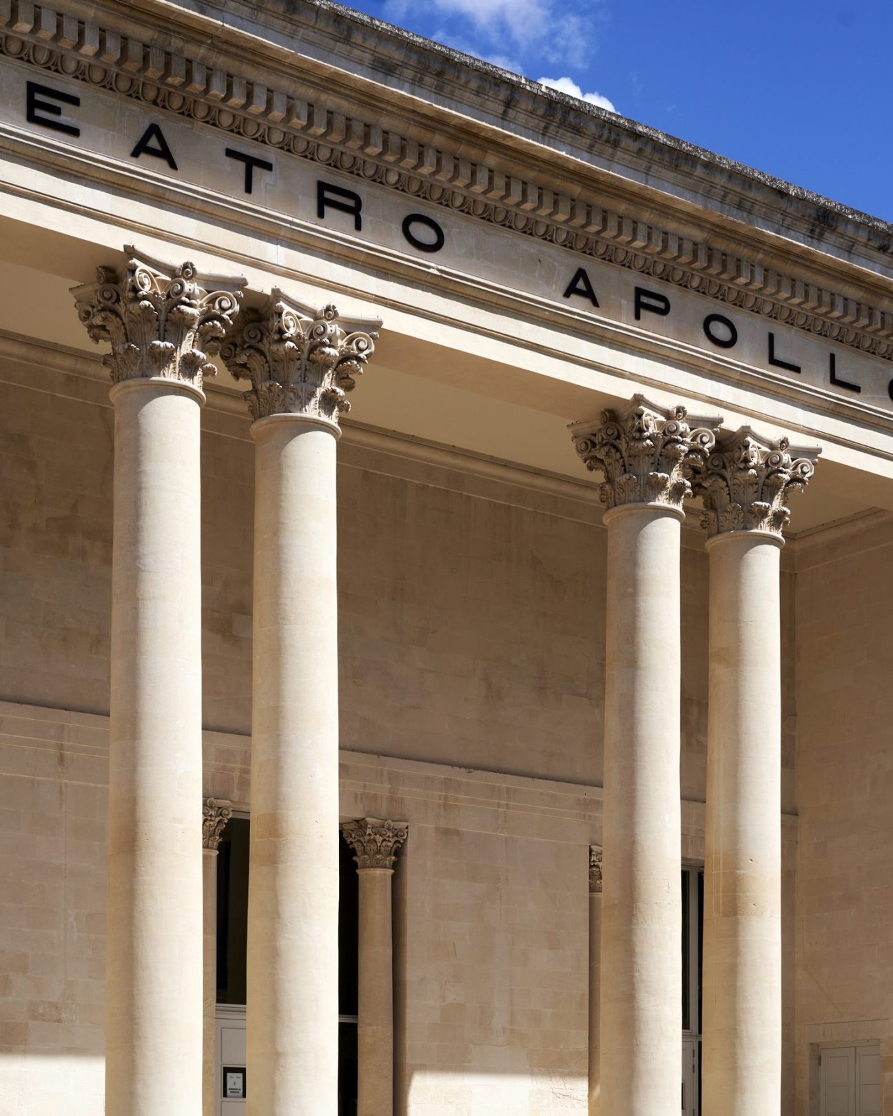 Neoclassical facade of Teatro Apollo in Lecce with four ornate Corinthian columns supporting a triangular pediment