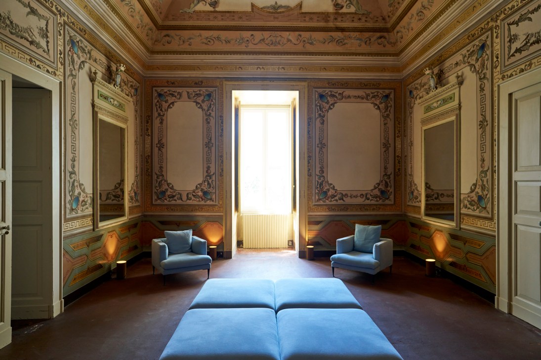 Ornate historical room with decorated ceiling, blue upholstered furniture and elaborate frescoed walls