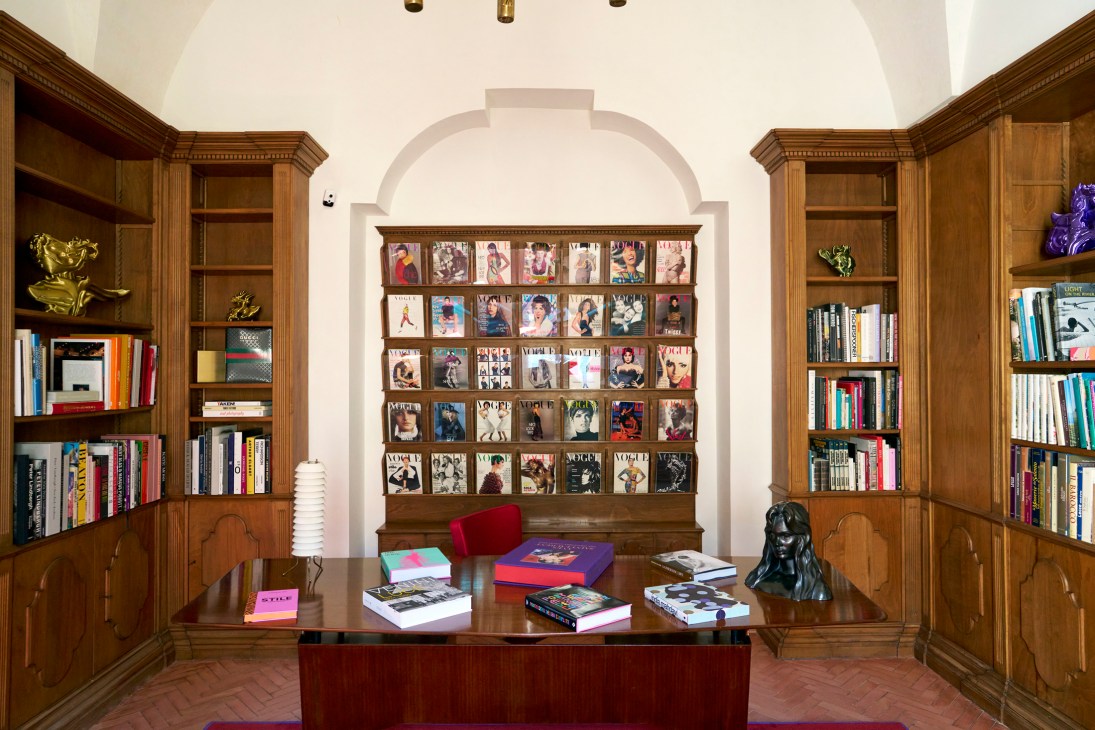 Elegant library room with floor-to-ceiling bookshelves, ornate ceiling, wooden desk and magazine display at Palazzo Luce