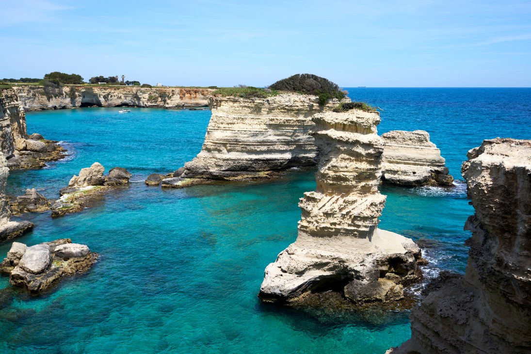 Dramatic limestone sea stacks rising from azure water at Torre Sant'Andrea