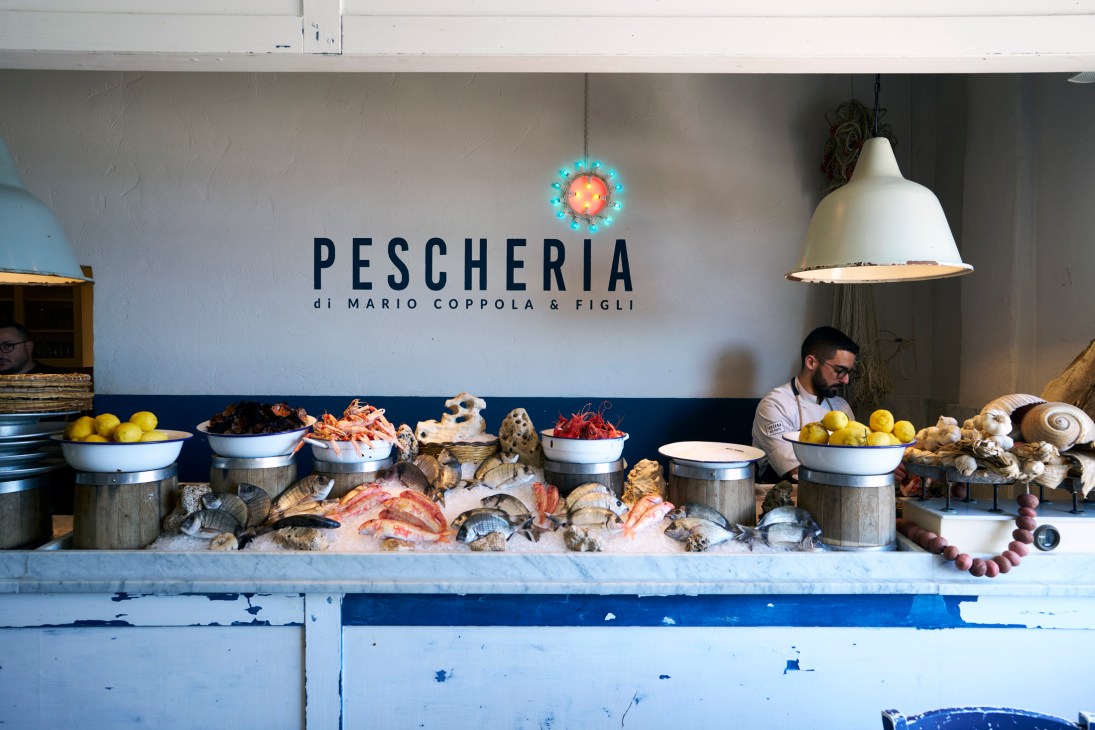 Fresh seafood display at Pescheria di Mario Coppola & Figli with fish counter and staff member