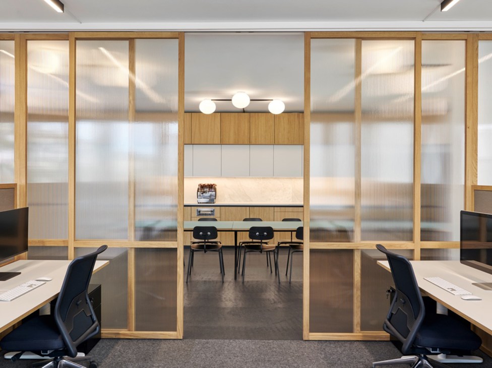Modern office space with glass partition walls, wooden frames, and contemporary furniture in open-plan design