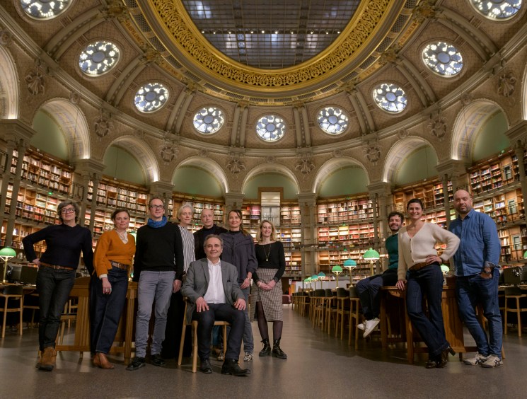 Group of eleven people posing together in ornate library with domed ceiling and circular bookshelves