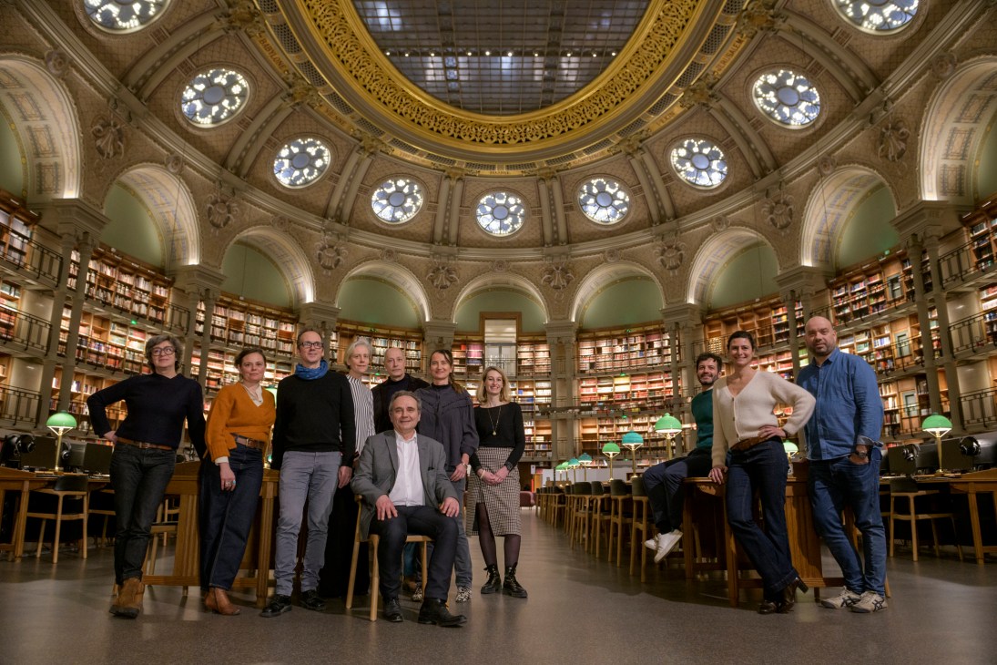 Group of eleven people posing together in ornate library with domed ceiling and circular bookshelves