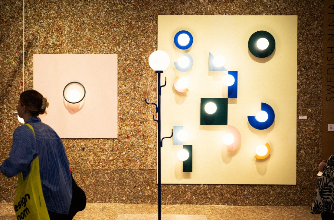 Modern lighting displays with circular and geometric shapes mounted on gallery wall with visitor viewing artwork
