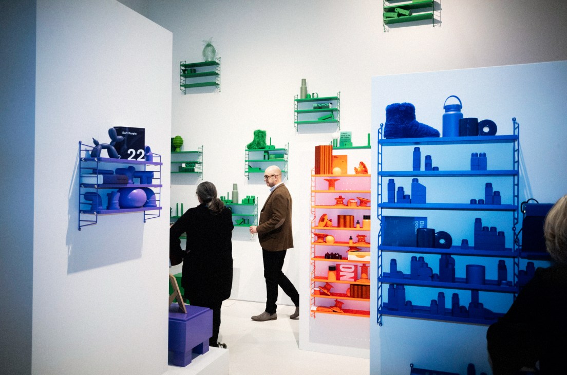 String Furniture's colorful modular shelving display with green, blue and orange wall-mounted units at Stockholm trade fair