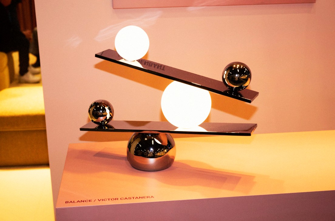 Artistic display by Victor Castanera of a modern sculptural balance lamp with chrome spheres and white orbs on a black seesaw