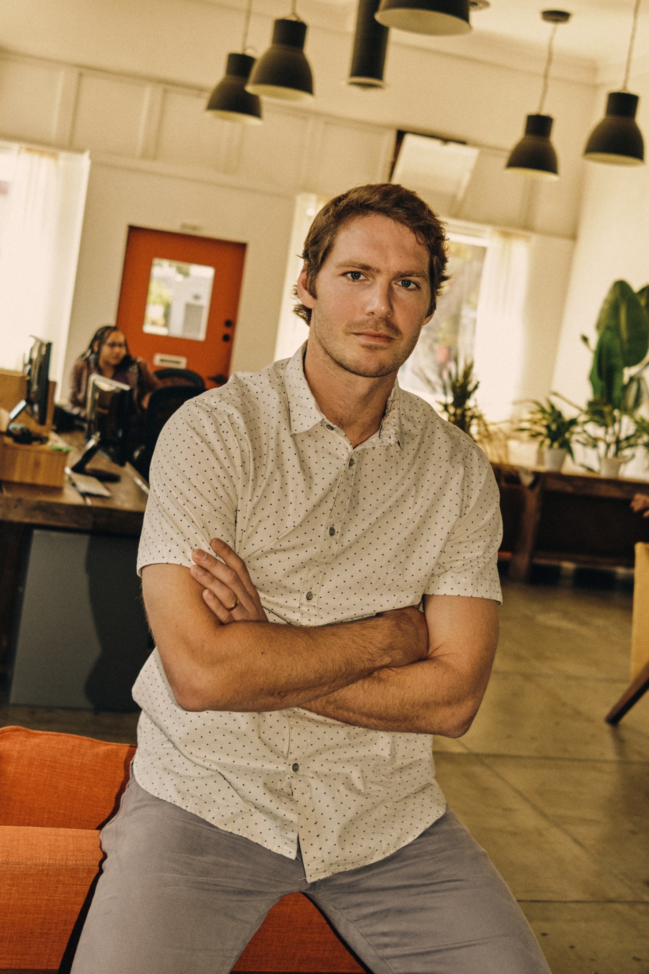 Graham Dugoni, founder of Yondr, stands with crossed arms in a modern office space with pendant lighting