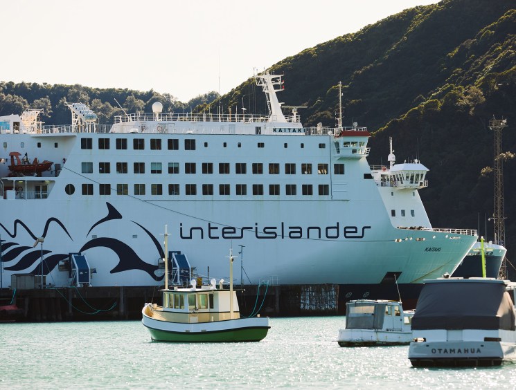 Interislander ferry docked in a harbour with small boats nearby.