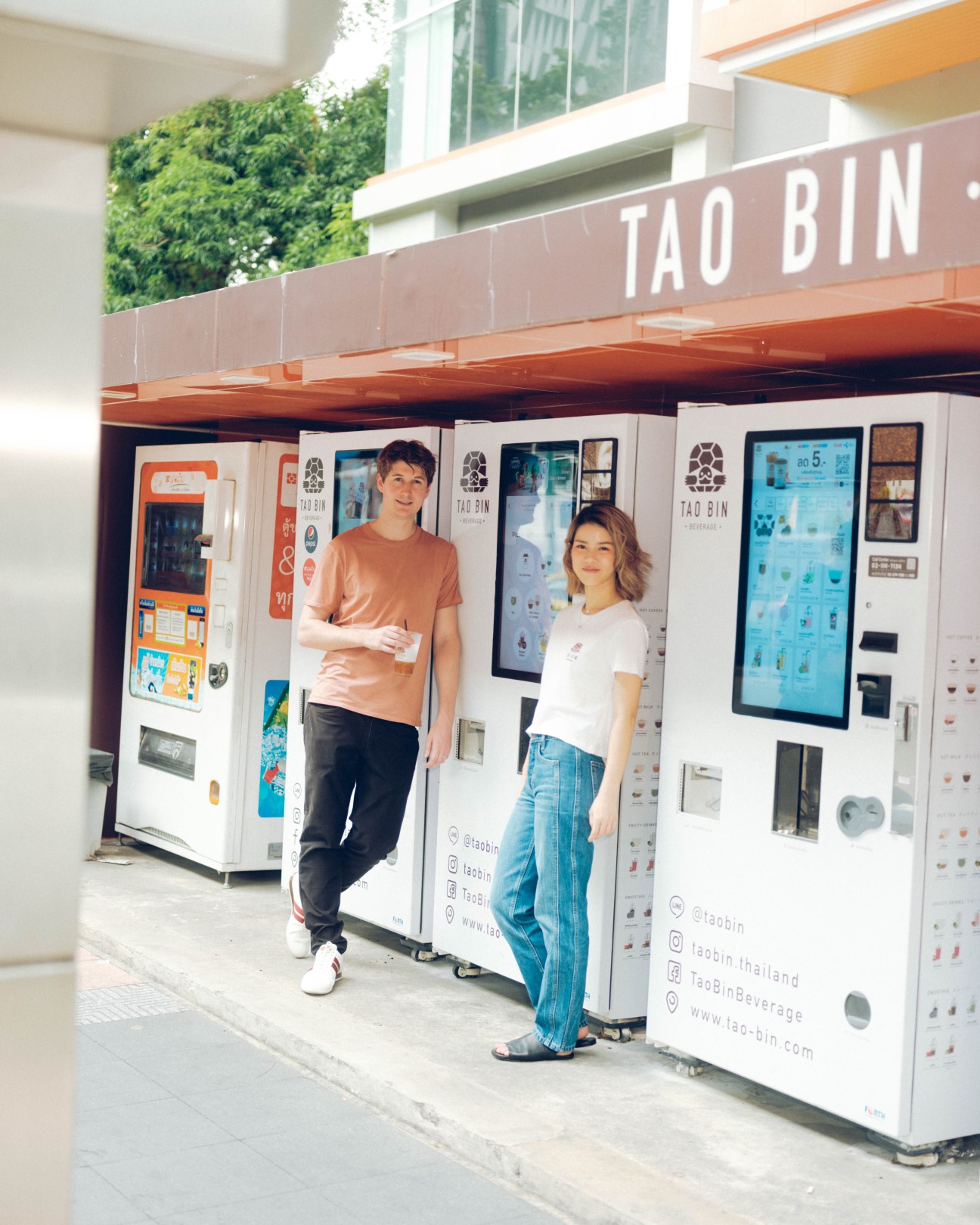 CTO Thomas Morrison and CEO Watanya Amatanon standing together in front of Tao Bin vending machines