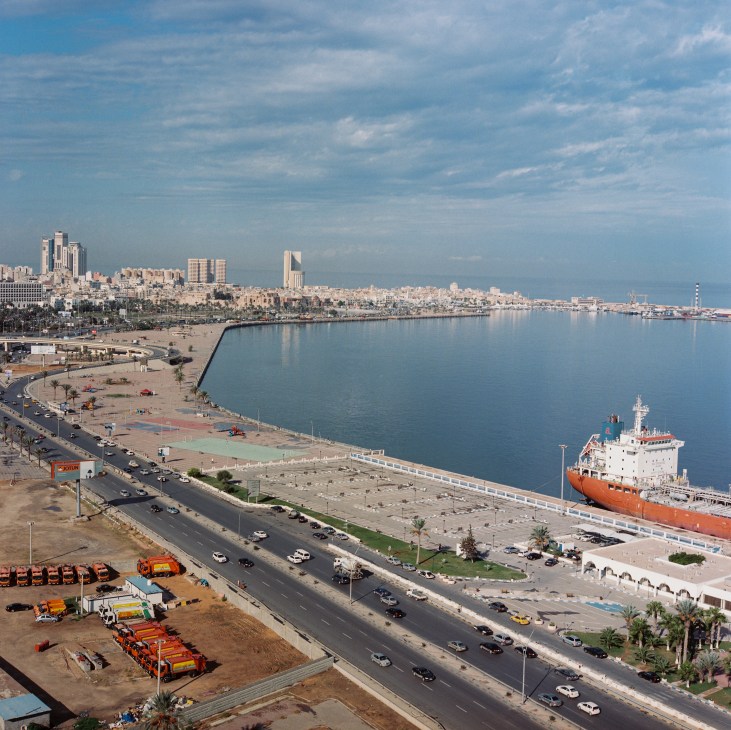 Aerial view of Tripoli's coastline showing urban development, harbor with docked ship, and Mediterranean Sea