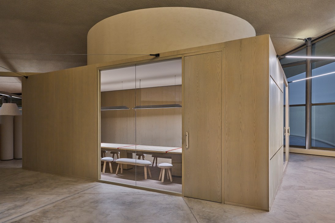 Modern wooden office pod with glass doors and interior meeting table designed by Agata Kurzela.
