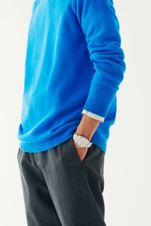Model wearing a bright blue Johnstons of Elgin jumper, dark trousers, and a Tag Heuer Carrera watch.