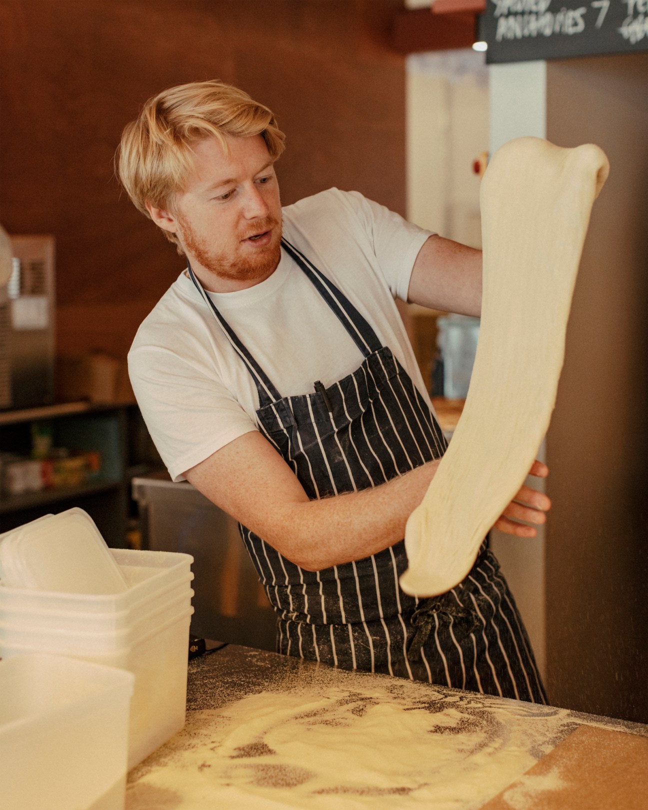 Baker in striped apron working with dough at Big Jo bakery showing flour milling process
