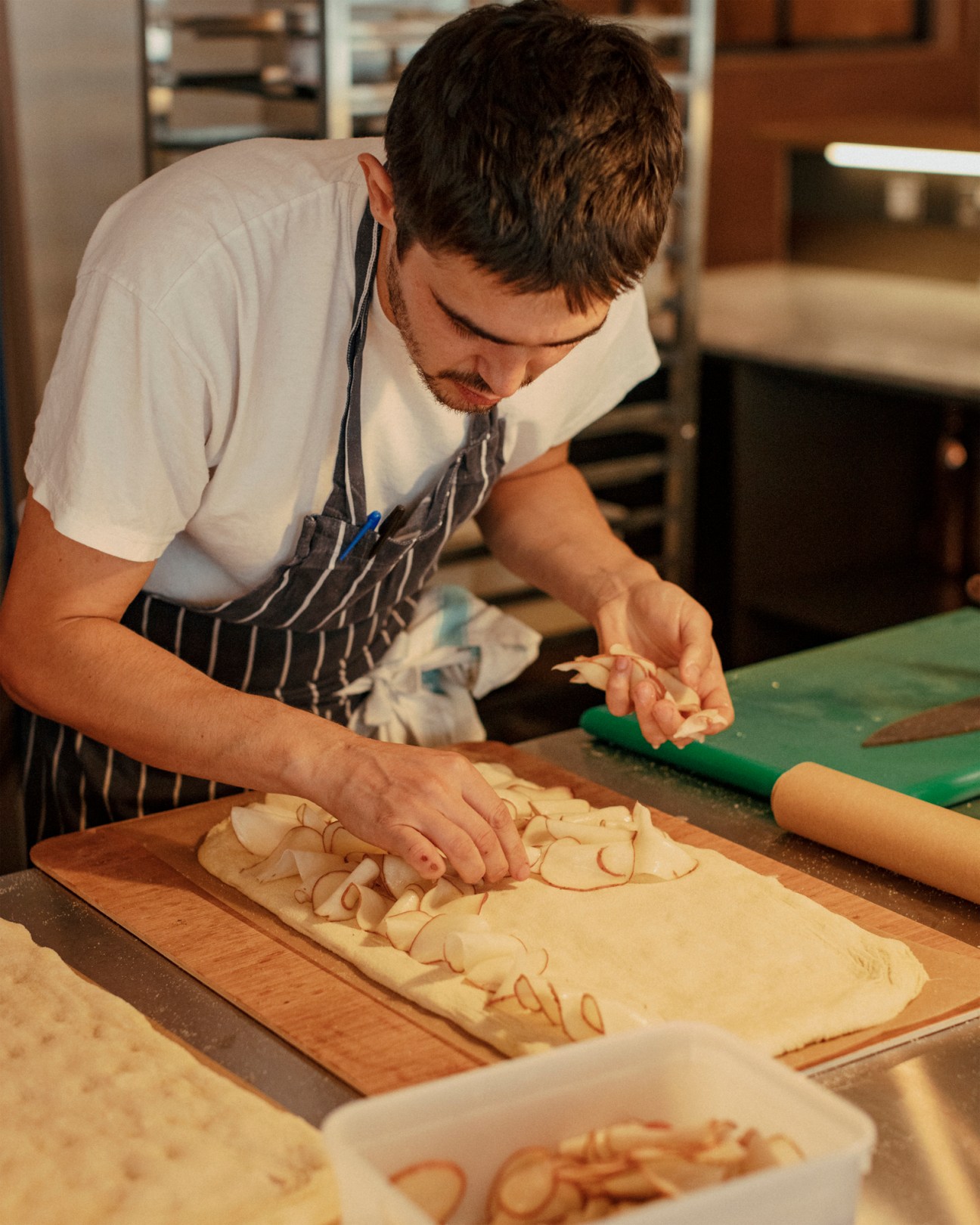 Chef arranging sliced onions on rolled dough at Big Jo bakery
