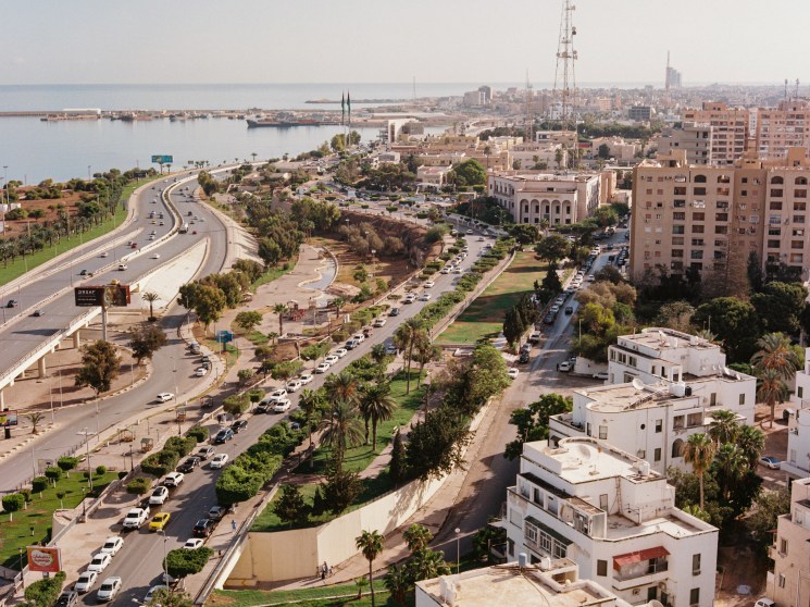 Aerial view of a coastal city with a palm-lined boulevard and harbour.