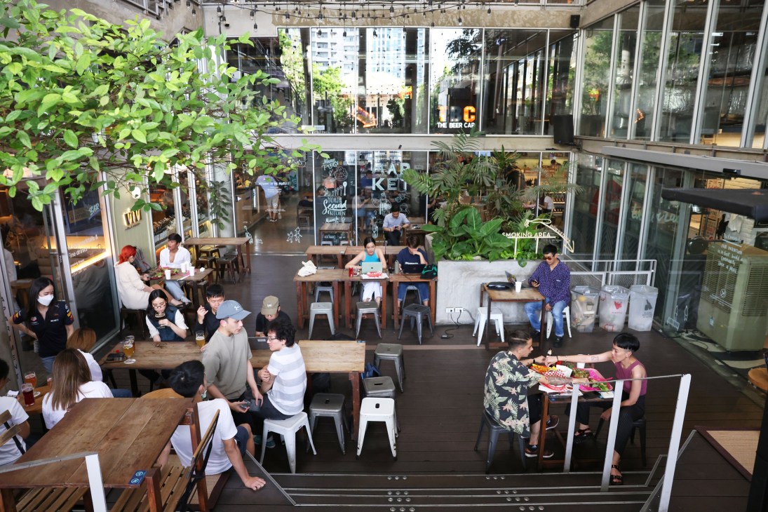 Aerial view of multi-level dining space with people seated at tables and modern glass architecture