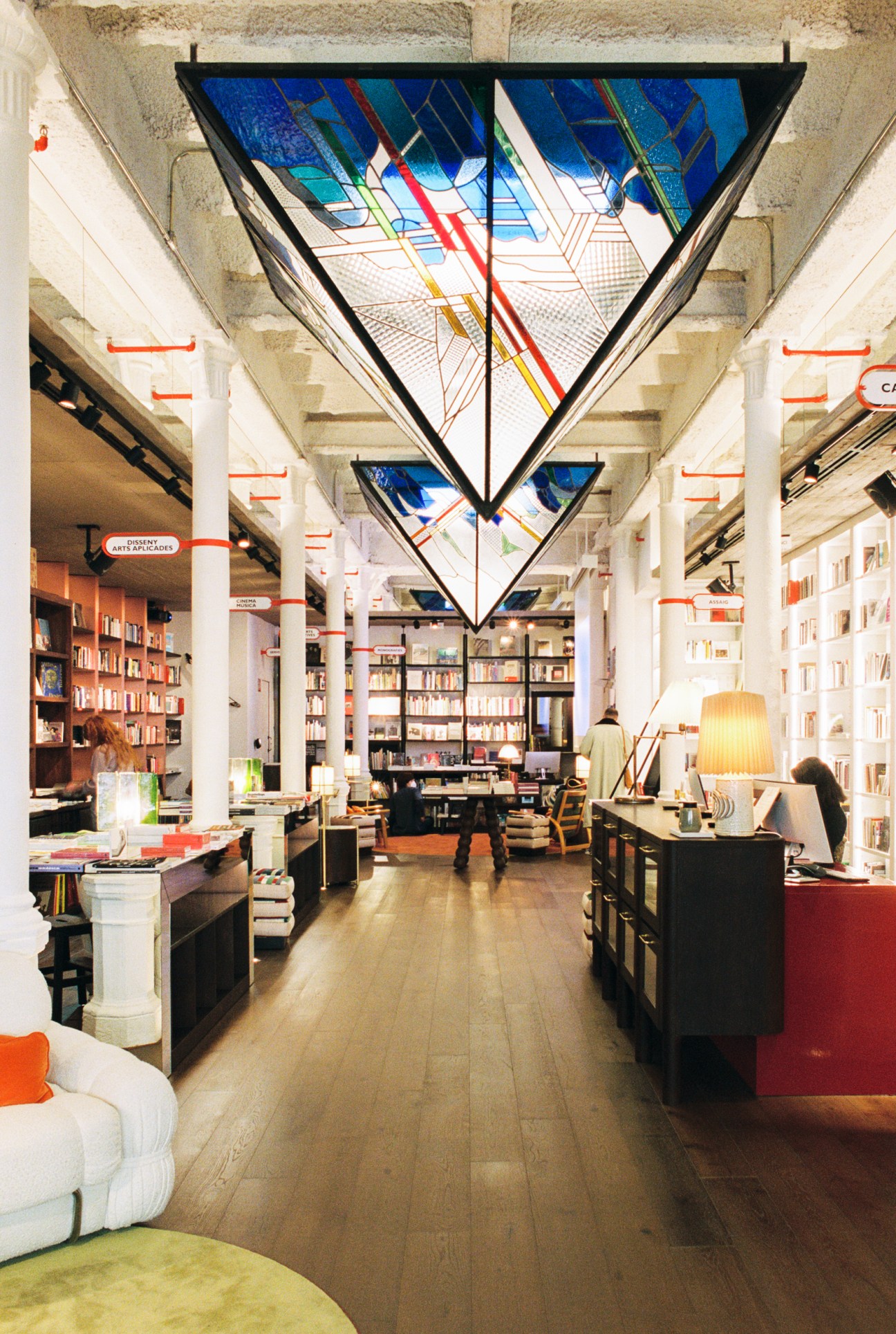 Modern bookstore interior with geometric triangular art installation hanging from ceiling above book displays
