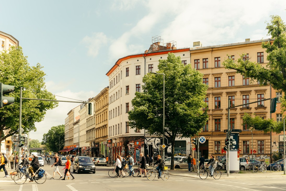 Oranienstrasse in Berlin's Kreuzberg district with historic buildings, cyclists, pedestrians and street-level shops.