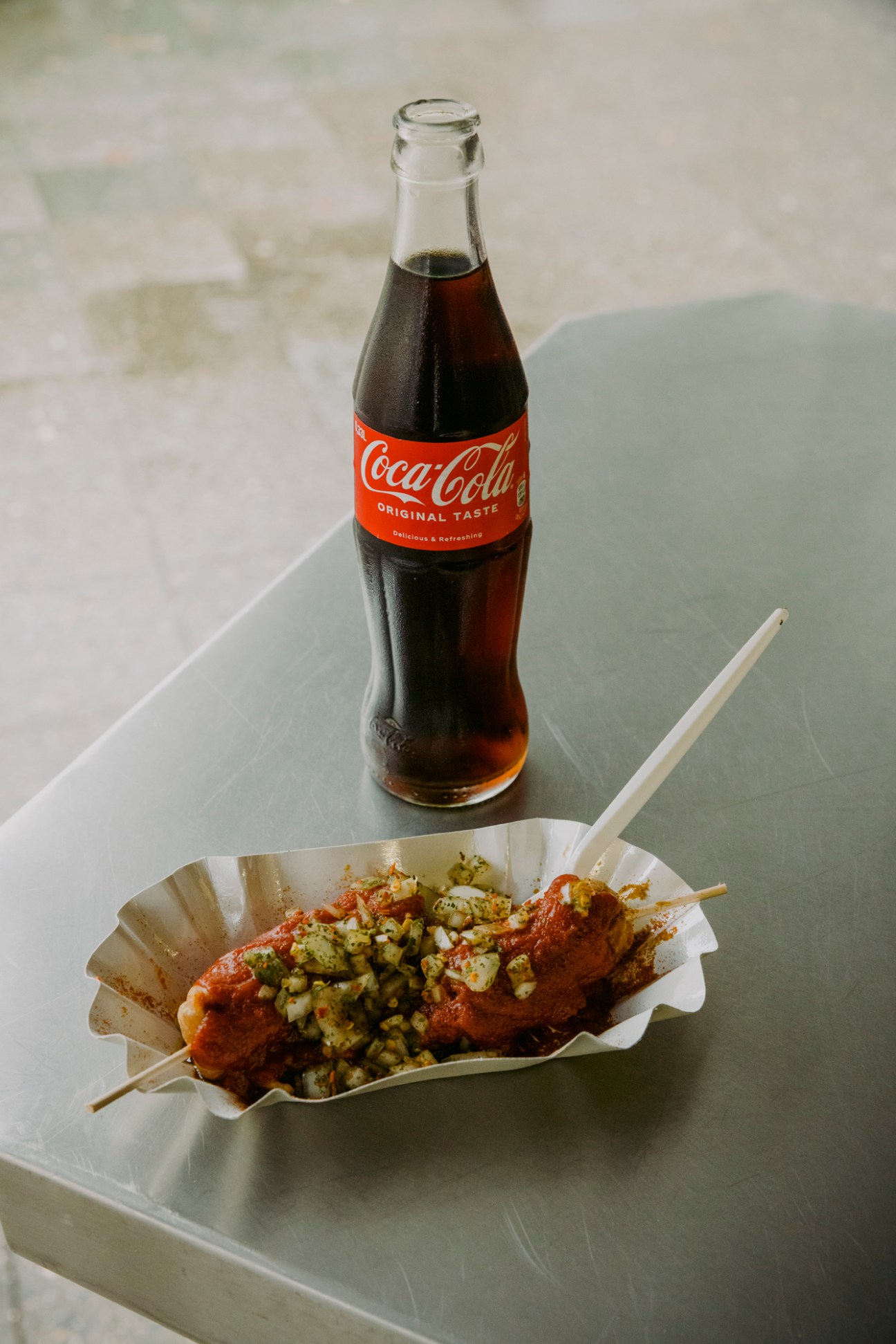 Currywurst served with french fries and Coca-Cola bottle on white table