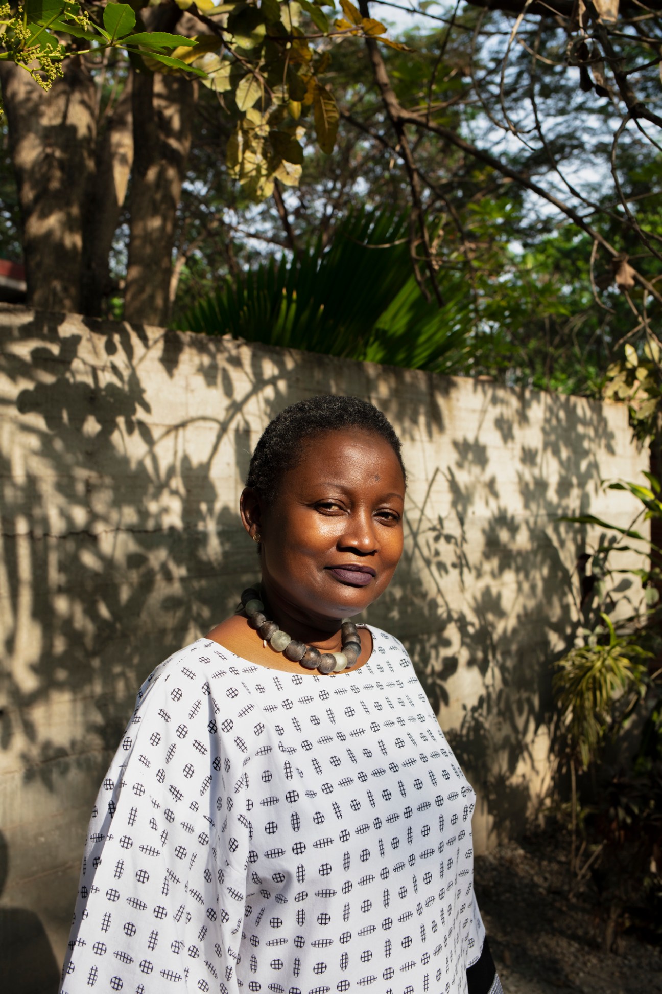 Odile Tevie, Director of Nubuke Foundation, wearing a patterned white top and beaded necklace outdoors