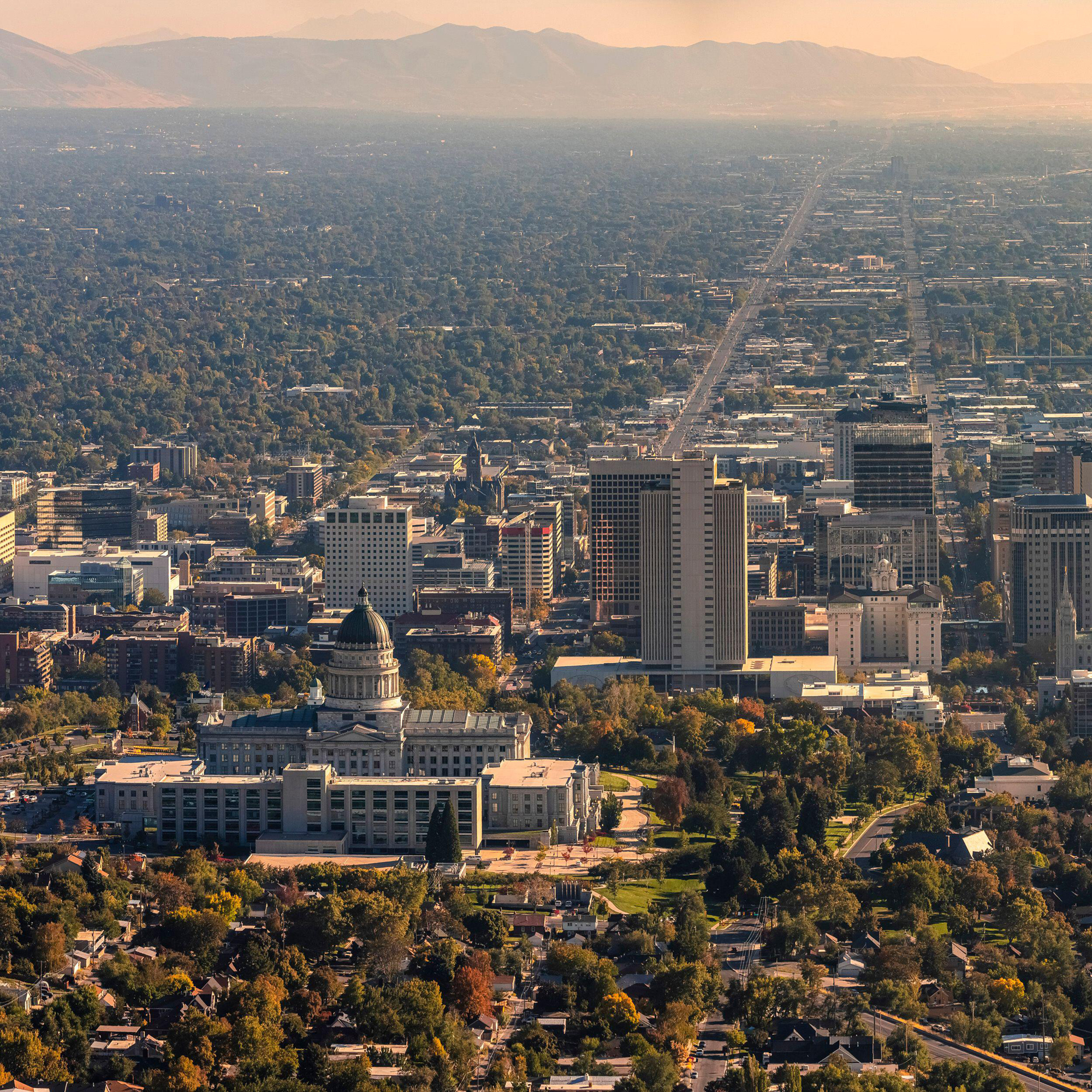Aerial view of Salt Lake City showing the Capitol building, downtown skyline, mountains and urban development.