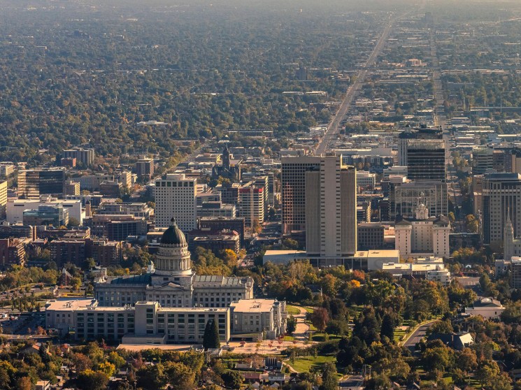 Aerial view of Salt Lake City showing the Capitol building, downtown skyline, mountains and urban development.