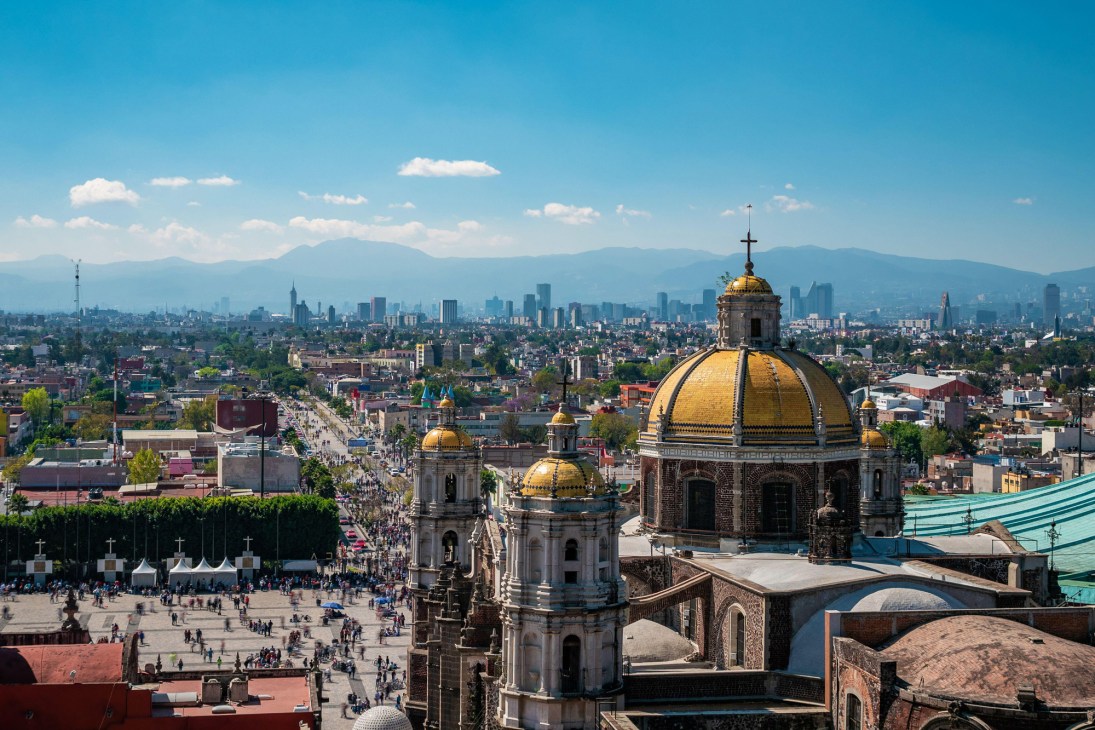 Aerial view of Mexico City showing colonial church with golden dome and sprawling urban landscape