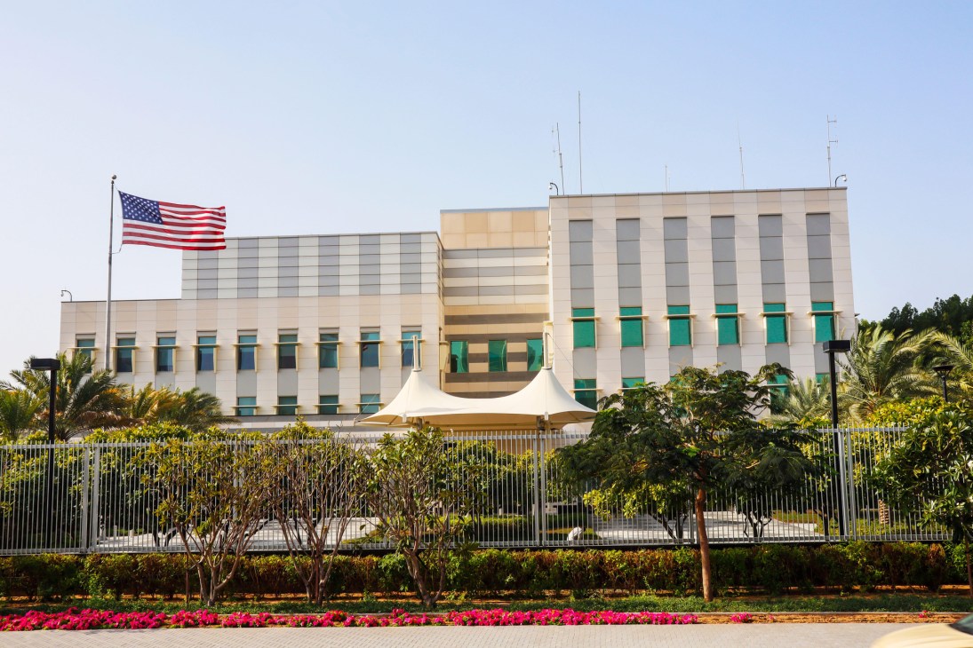 Modern government building with American flag and security fence surrounded by landscaping