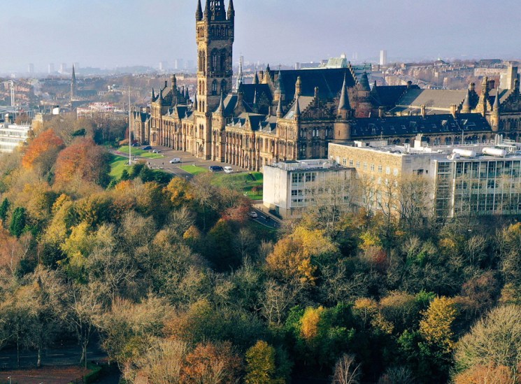 Aerial view of Glasgow showing historic university buildings with gothic spire and autumn parkland