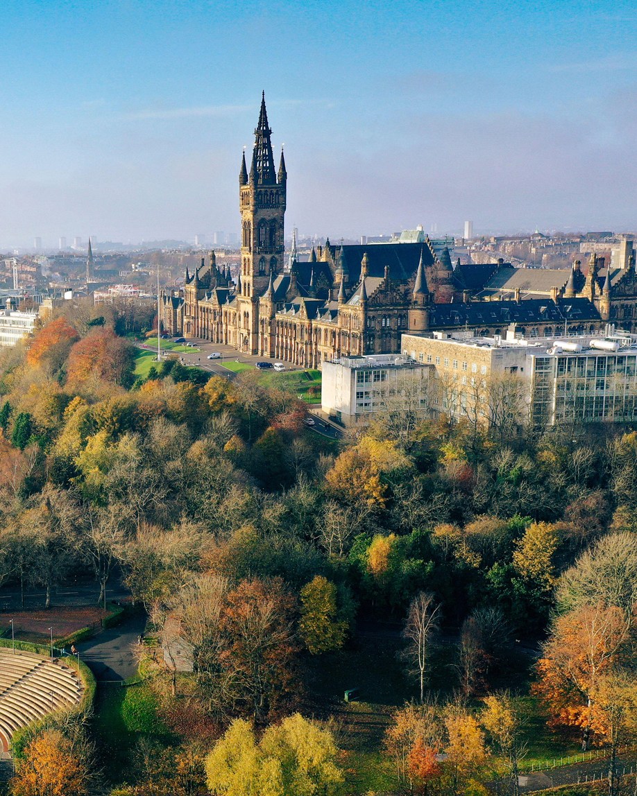 Aerial view of Glasgow showing historic university buildings with gothic spire and autumn parkland