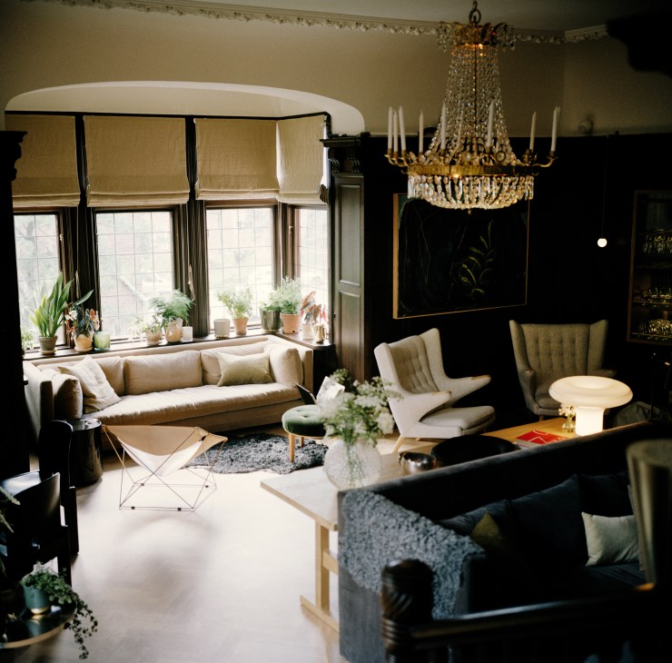 Ett Hem's lounge with crystal chandelier, bay window seating, and mix of vintage and modern furniture