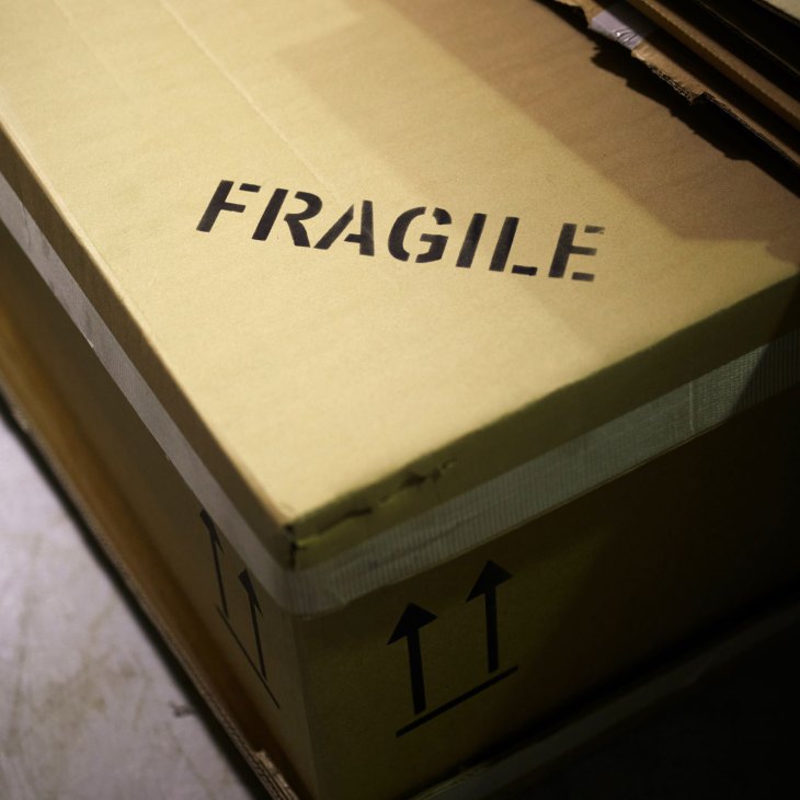 Cardboard box labeled FRAGILE with directional arrows in storage facility