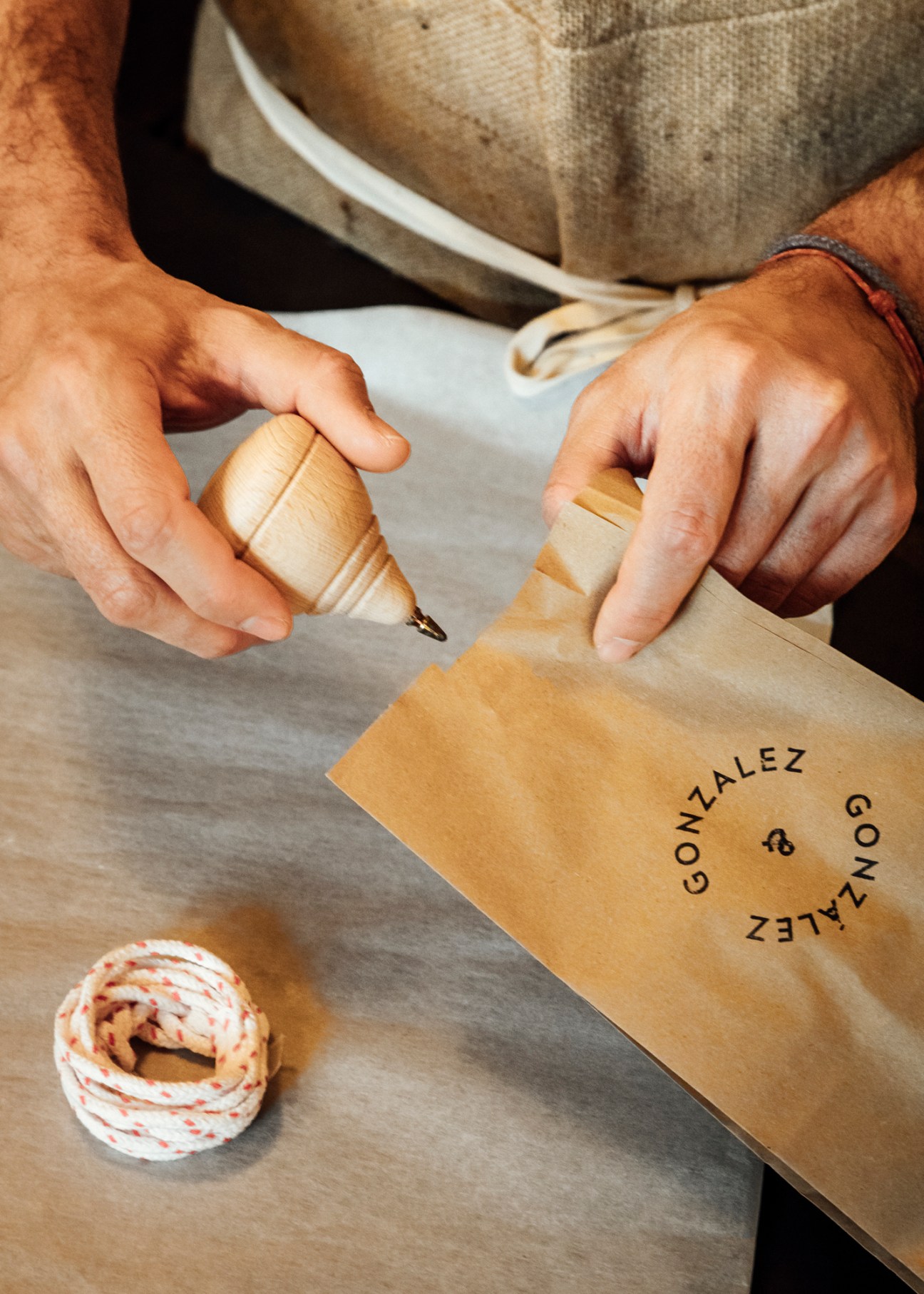 Close-up of hands using a wooden stamp on a brown paper bag