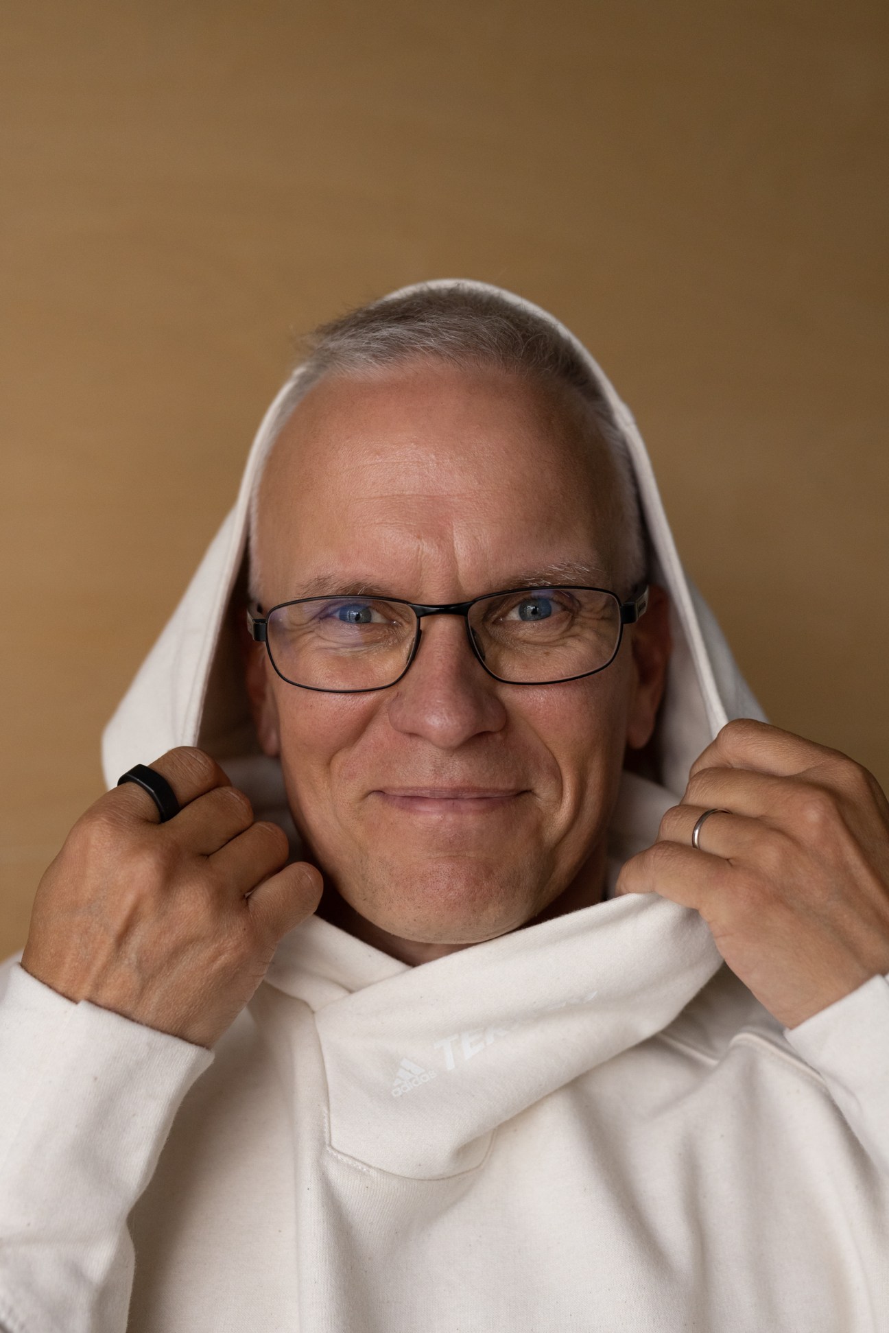 Portrait of Janne Poranen wearing a white hoodie in an industrial setting