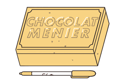Gold Sharpie pen displayed alongside notebooks in vintage Menier chocolate box