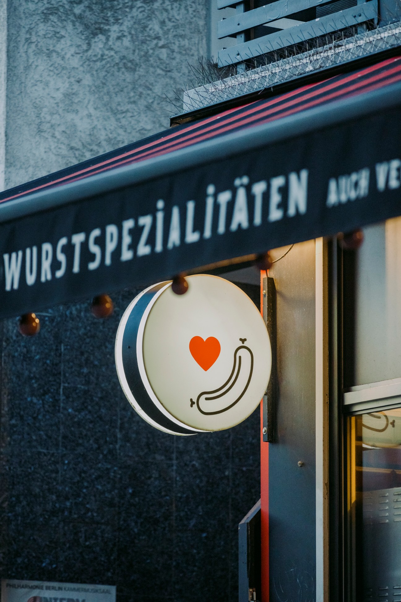 Exterior storefront of Wurstspezialitaten with circular logo featuring heart symbol and sausage design