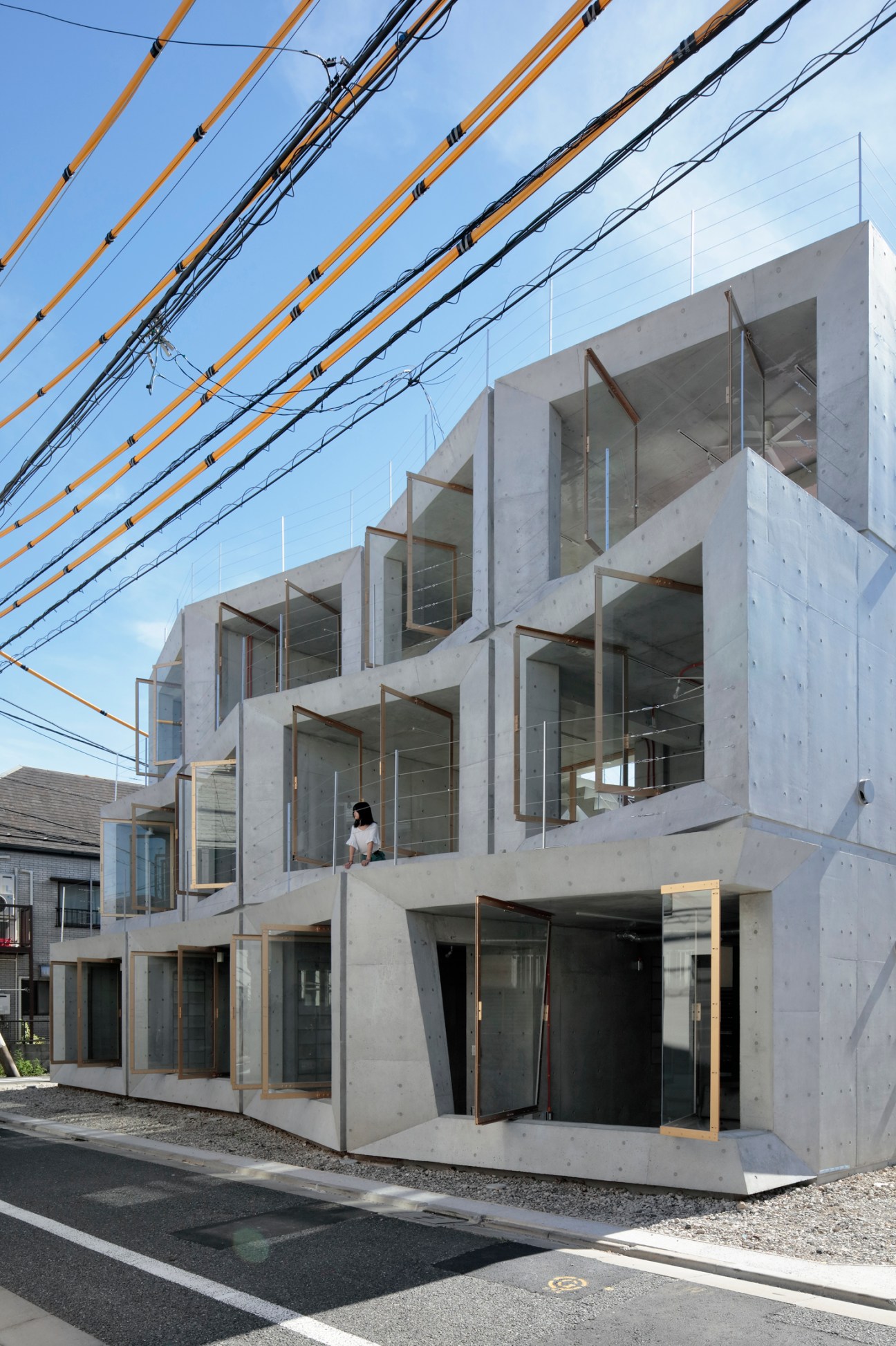Modern concrete residential building with large geometric windows and glass panels in Tokyo neighborhood