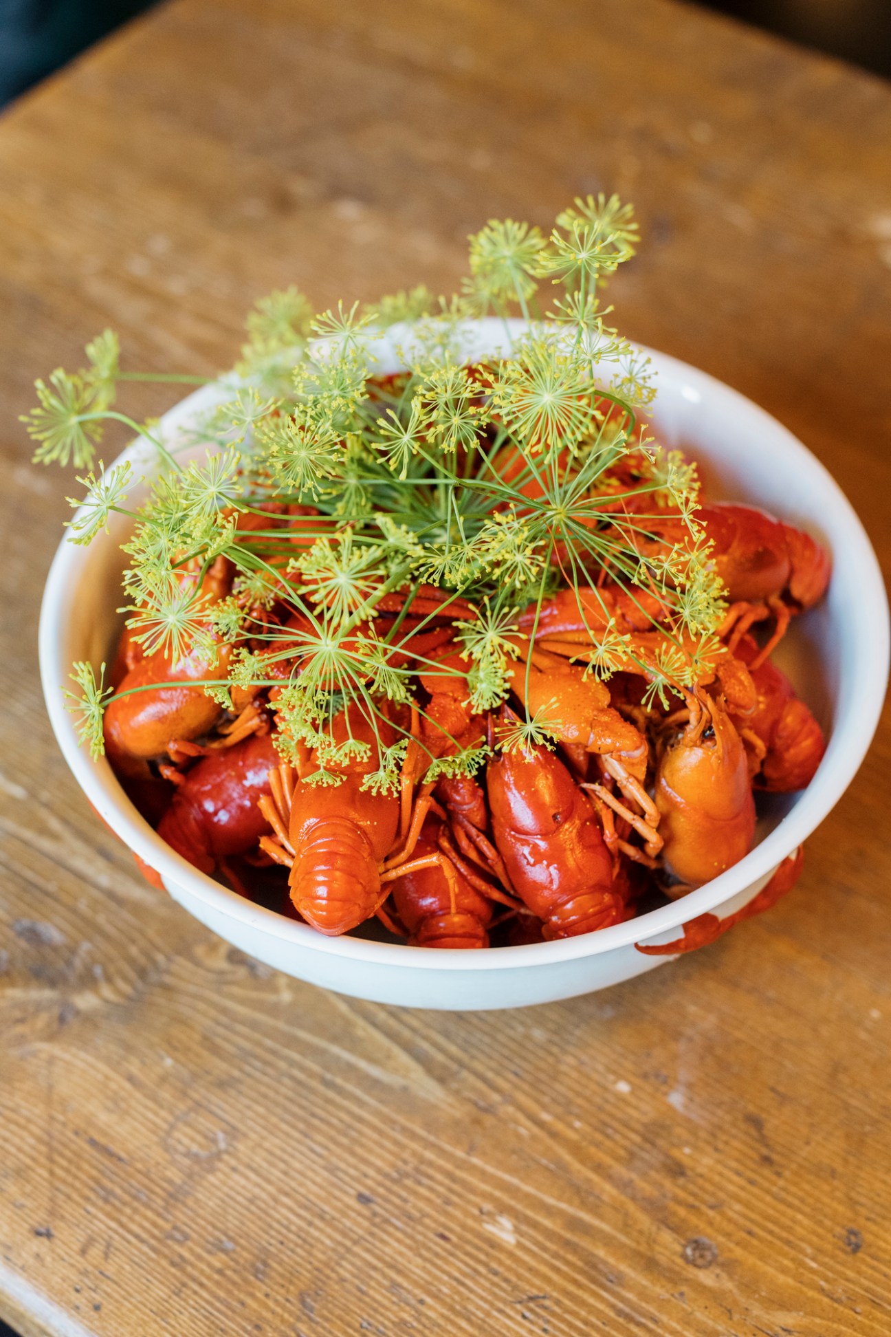 Cooked crayfish garnished with fresh dill in a white bowl