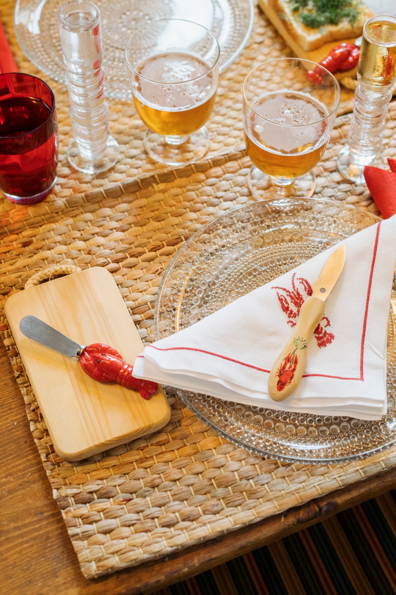 Traditional crayfish eating implements including small knife and crackers on woven placemat with napkins and glassware