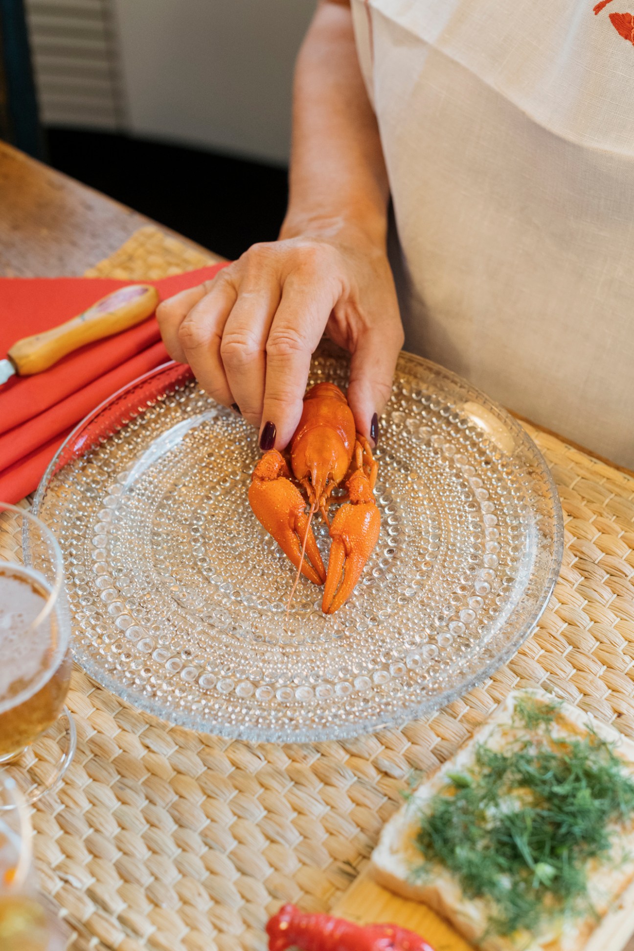 Hand placing Finnish wild river crayfish on an Iittala Kastehelmi glass plate