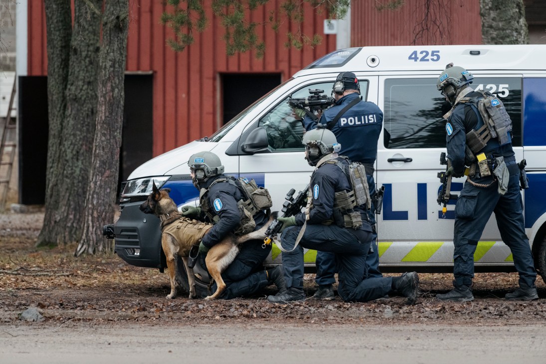 Police special forces in tactical gear with weapons positioned around a police van with a dog