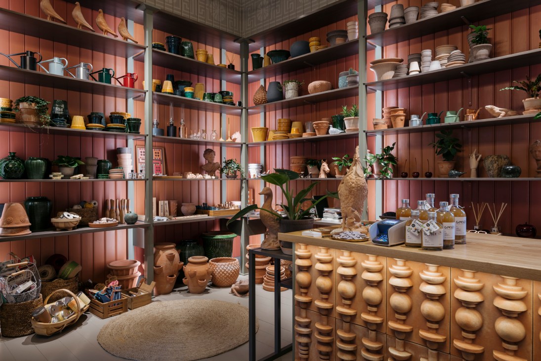Interior of Cigale & Fourmi design shop displaying pottery, homewares and plants on shelves against coral-pink walls.