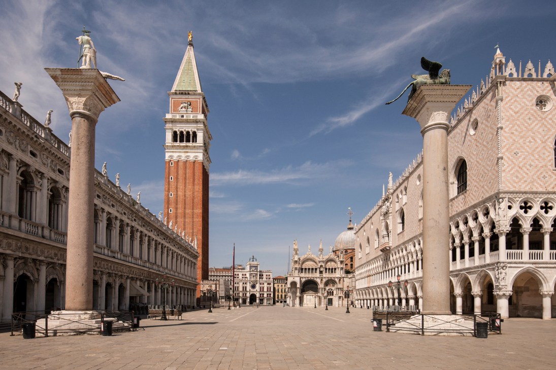 St Mark's Square in Venice during lockdown, empty of tourists with historic buildings and bell tower under clear sky.